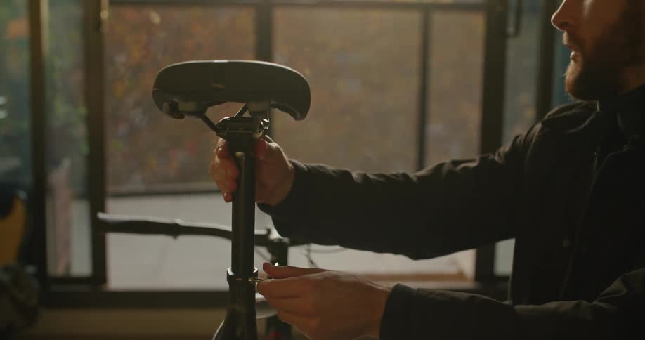 Young man assembling a bicycle on the living room at sunset