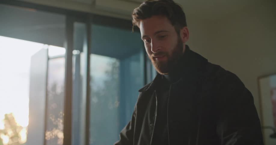 Young bearded man unpacks a bicycle in the living room at home