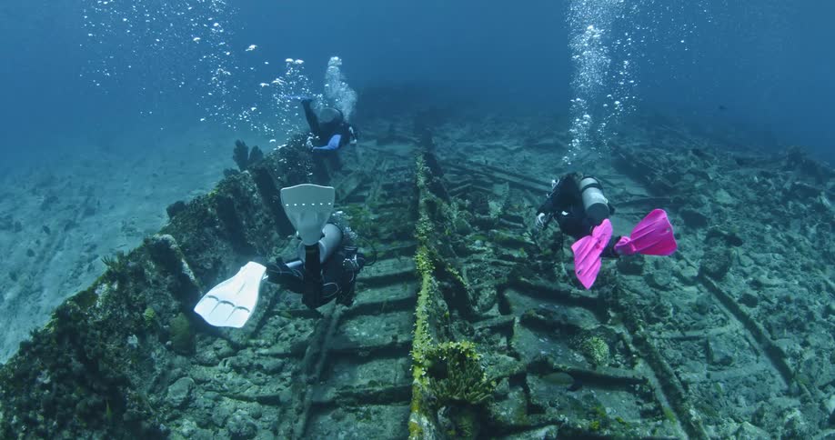 Scuba divers swimming amongst some wreckage