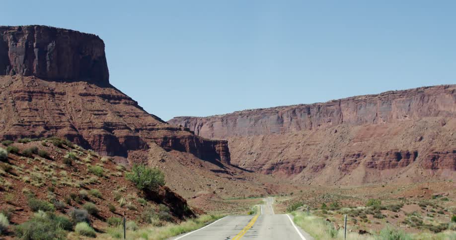 Moving down an empty two lane road with high rocks all around