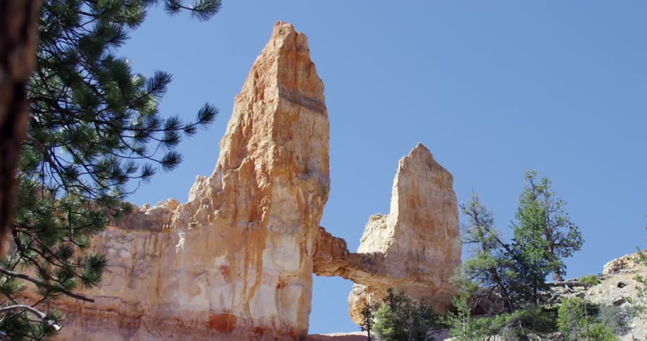 A large rock formation reaches into a sunny sky