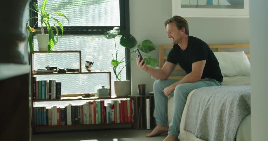 A man talking on a phone while a dog lays on the floor