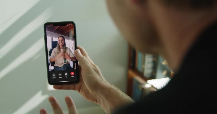 Woman who is on an iphone screen face time blowing a kiss and waving goodbye