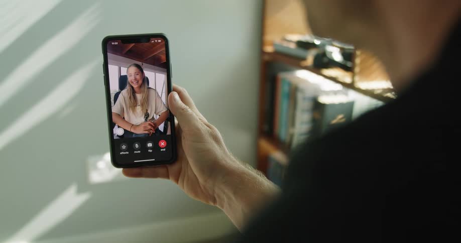 A man and woman smiling and chatting over video on a smartphone