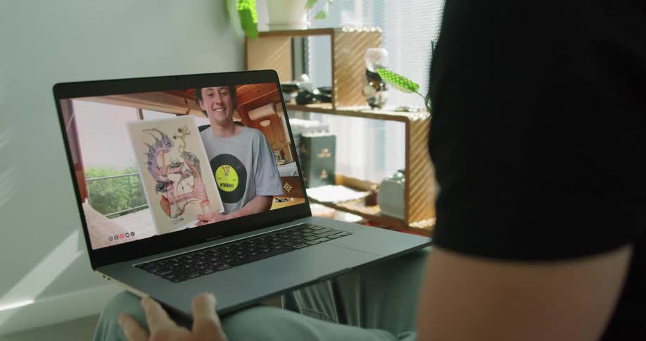 A man holds up a drawing while having a video chat via computer