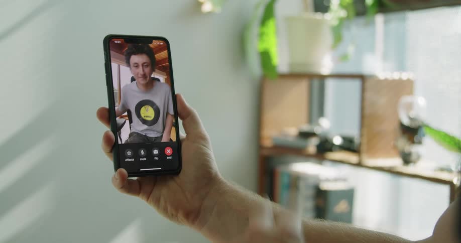 Man with a black shirt makes a video call on his iphone smartphone and shows peace sign