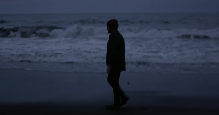 A person is walking along the beach at dawn