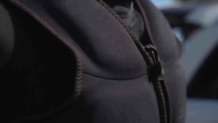 A man putting on a wet suit and life vest before kiteboarding