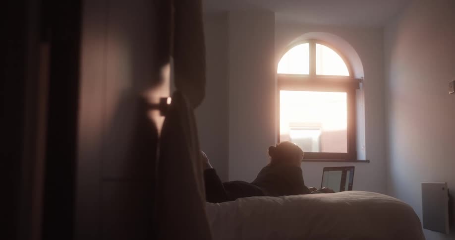 Woman relaxing in bed at home uses a laptop