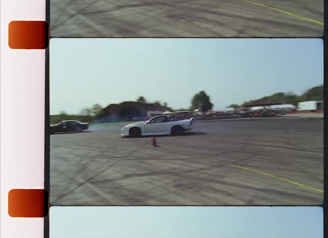 A trio of sports cars skid as they take a sharp turn around a makeshift racetrack