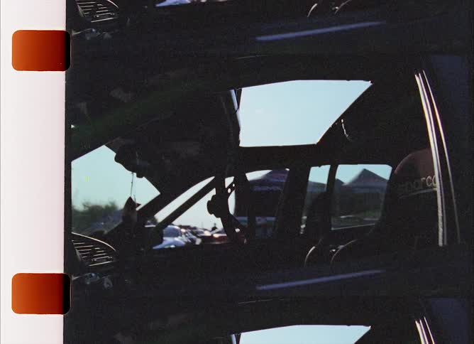A vehicle with a rearview mirror and a steering wheel with the sky and clouds in the background
