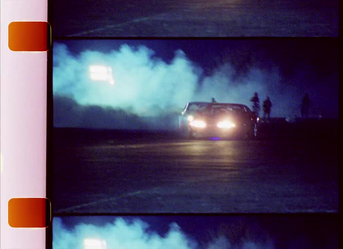 Race cars drifting on a street at night caught on vintage film
