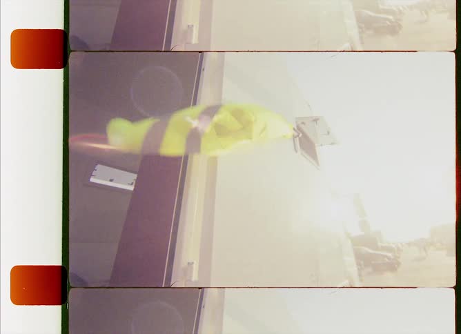 Yellow black barrier plastic piece flutters on side of trailer with open door near street as cars pass