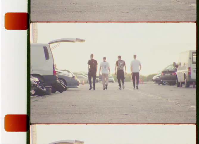 A filmstrip with teenage boys walking past cars parked in a lot