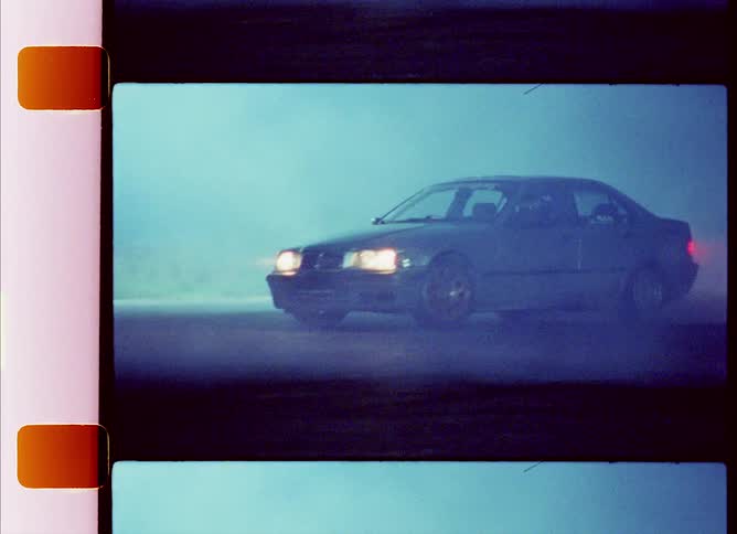 A car performs donuts on a smoky road at night