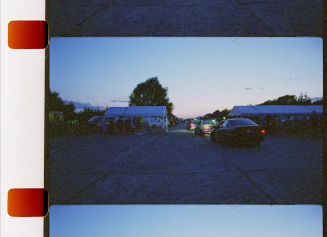 Vehicles driving with tents trees the sky and clouds in the background