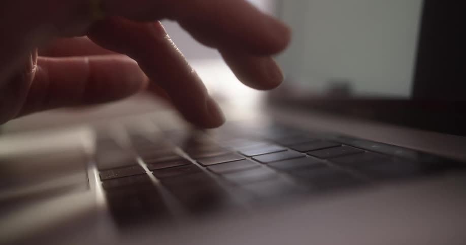 A woman in an office setting types on a laptop