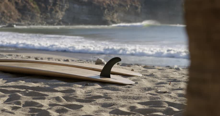 Surfboards lying on a beach at daytime next to the ocean