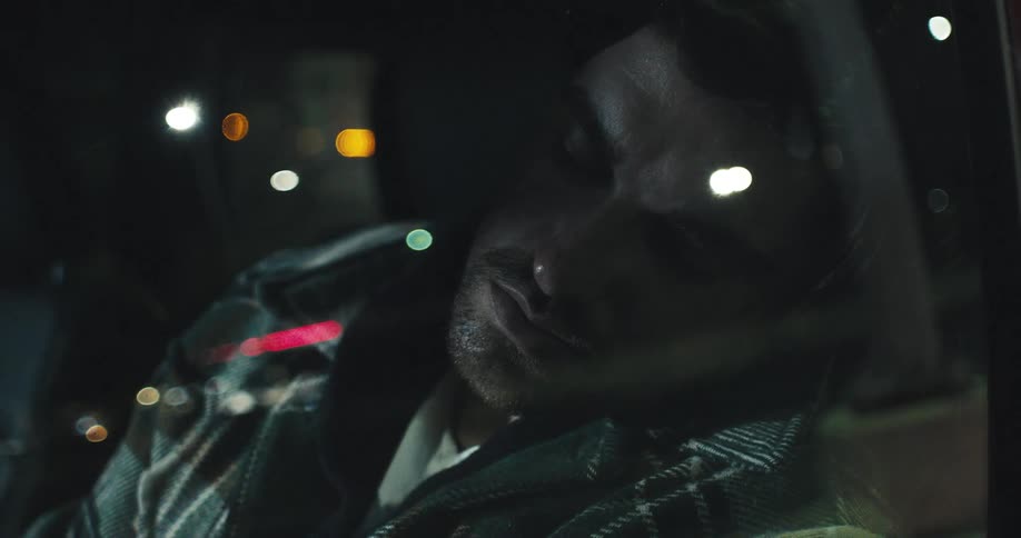 A man sleeps in a vehicle at night