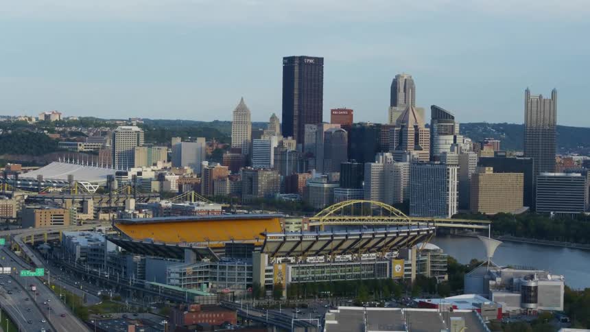 A modern sports stadium is located just across a river from a large metropolitan area