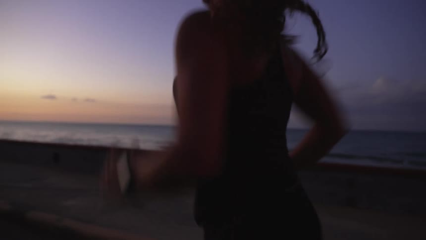 A woman running along the coast at dawn