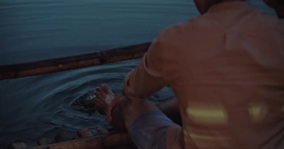 A person sitting by a lake submerging their feet on the water