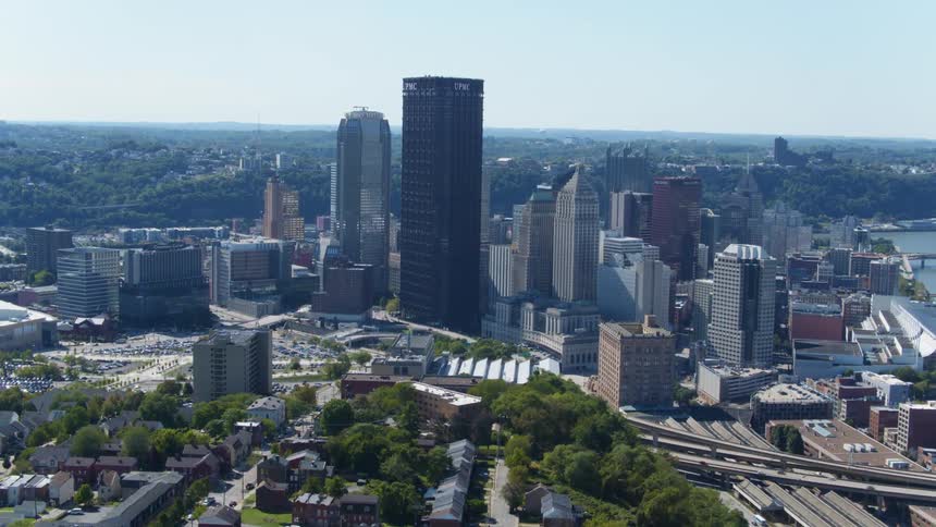 A skyscraper looms of a freeway and the surrounding city in a metropolis during the day