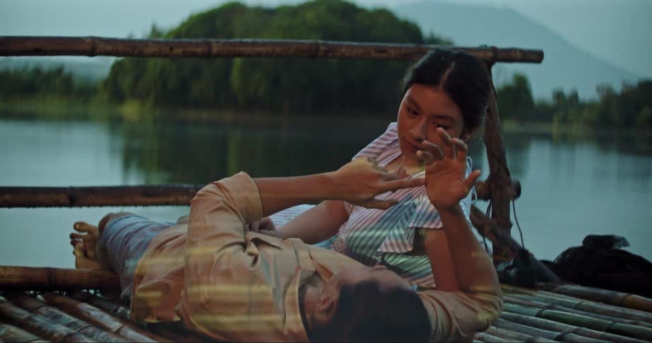 A man and woman lie on a dock and talk and laugh