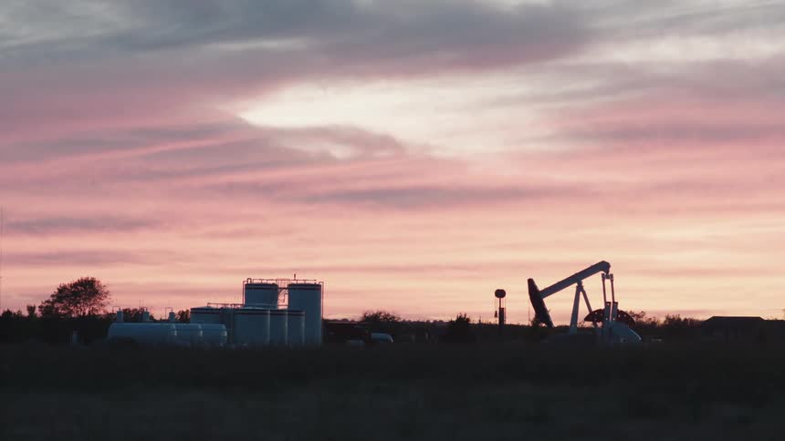 Oil pump moving on a field in the countryside at sunset