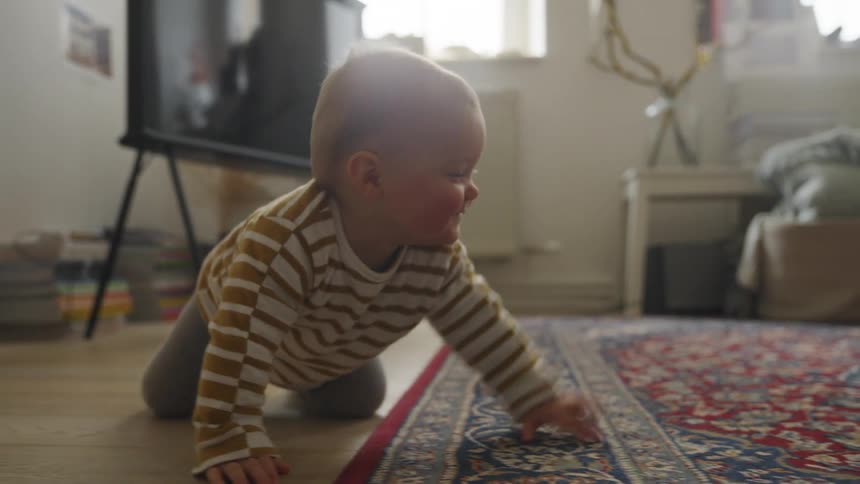 Baby crarwling on the floor of the living room at home