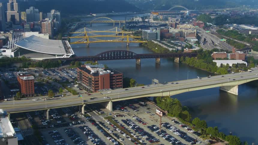 Multiple vehicles pass over a large city bridge over a river