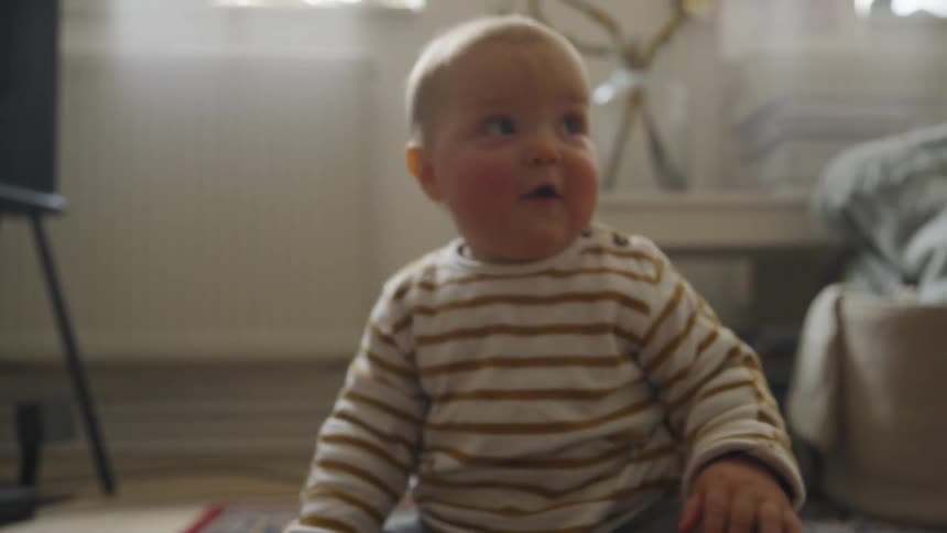 A young baby crawls and then sits up at home