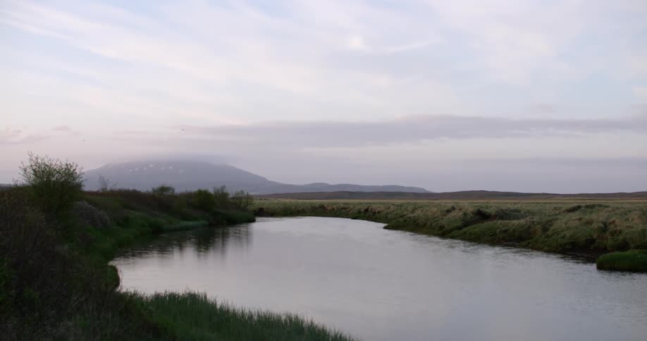 A large pond sits still in the wilderness