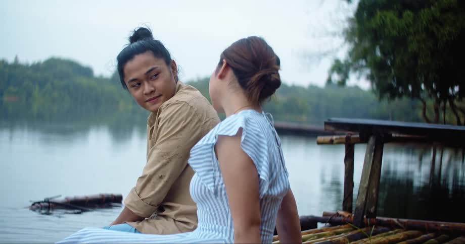 Man and woman sitting on the pier of a lake