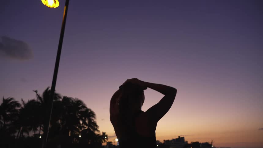Silhouette of an exhausted woman walking to the beach after a run