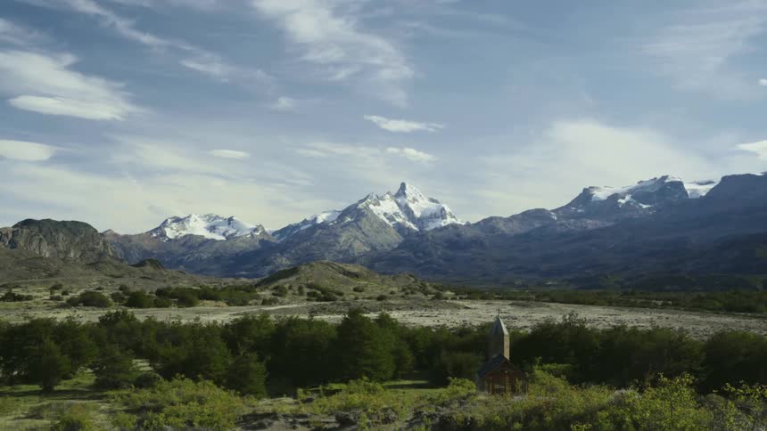 Bushes and trees with a mountain range in the distance under a cloudy sky