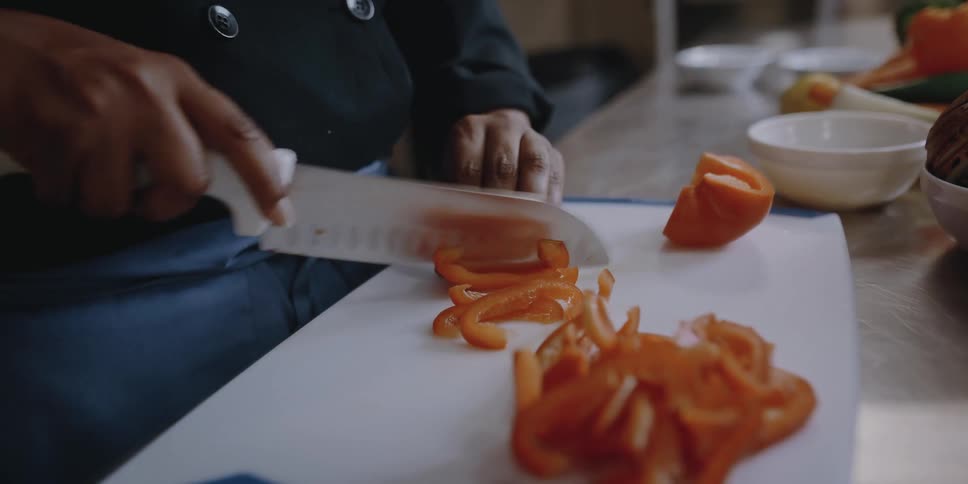 Female chef slicing vegetables on the kitchen of a restaurant