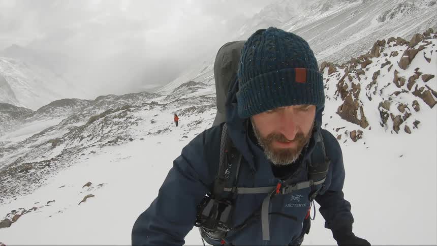 Man carrying a backpack climbs the snow covered slopes of a mountain