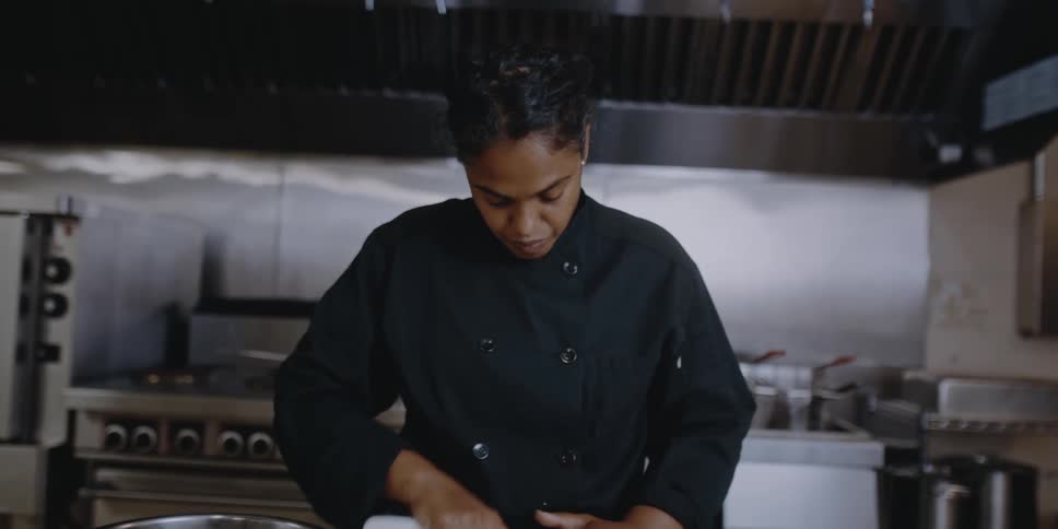 A chef uses a knife to chop food in a restaurant kitchen