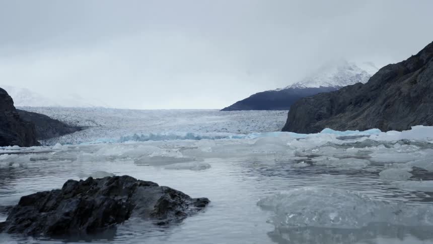 Ice floats in an arctic body of water on a cloudy day