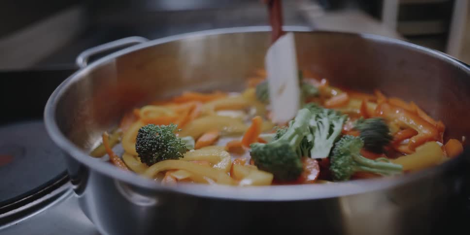Female chef cooking vegetables on a pan in the kitchen at a restaurant