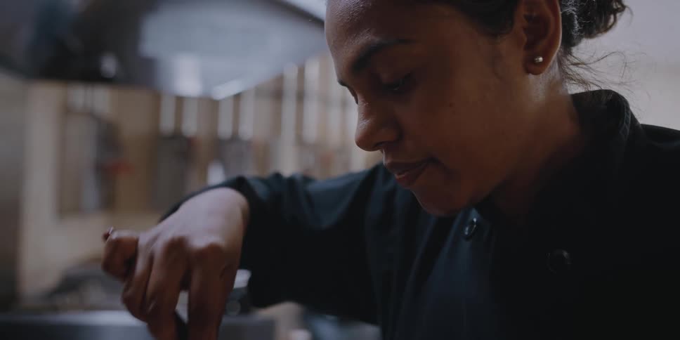 A woman is cooking while wearing a chefs uniform