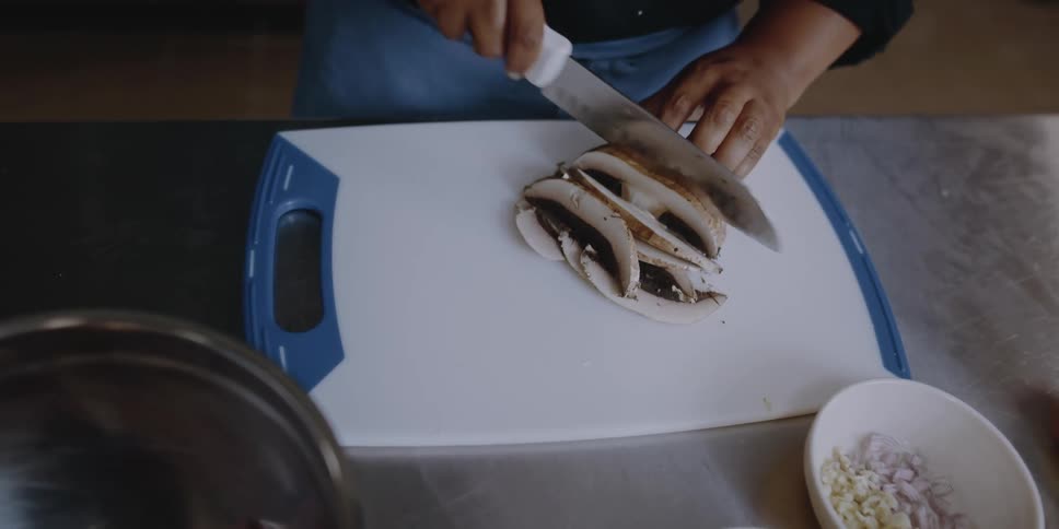 A person cutting food on a cutting board
