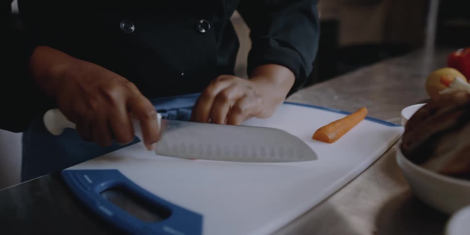 A person cutting a carrot on a cutting board