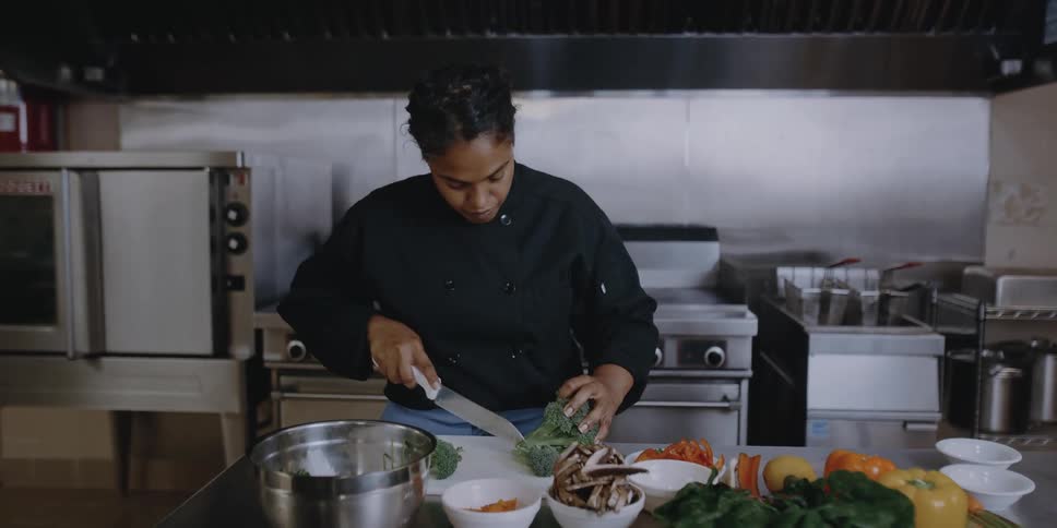 Female chef slicing broccoli with a kitchen knife on a restaurant