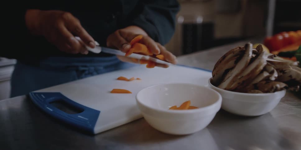 Female chef serving sliced carrots on the kitchen of a restaurant