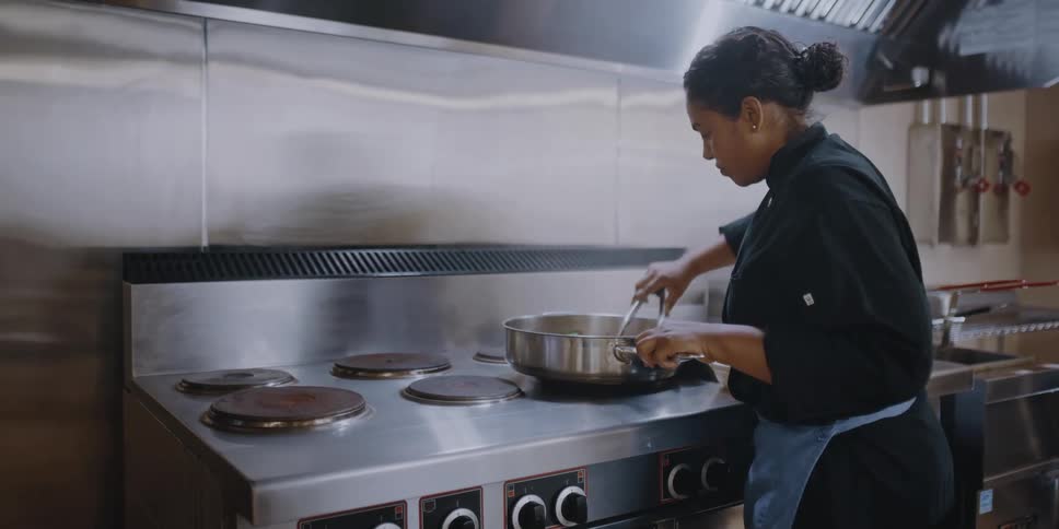 A woman cooking in a kitchen in a restaurant