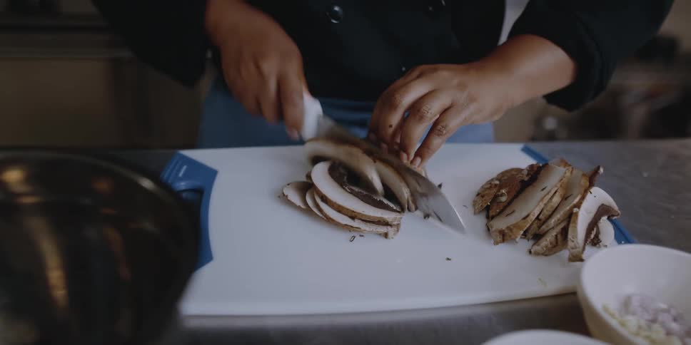 Someone is cutting large mushrooms with a sharp knife