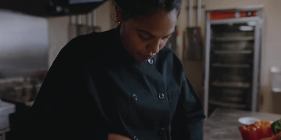 Female chef slicing vegetables on the kitchen of a restaurant