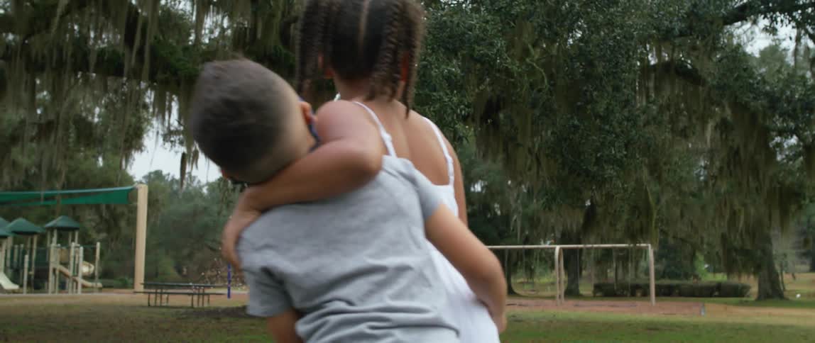 Two children hugging outdoors in a park